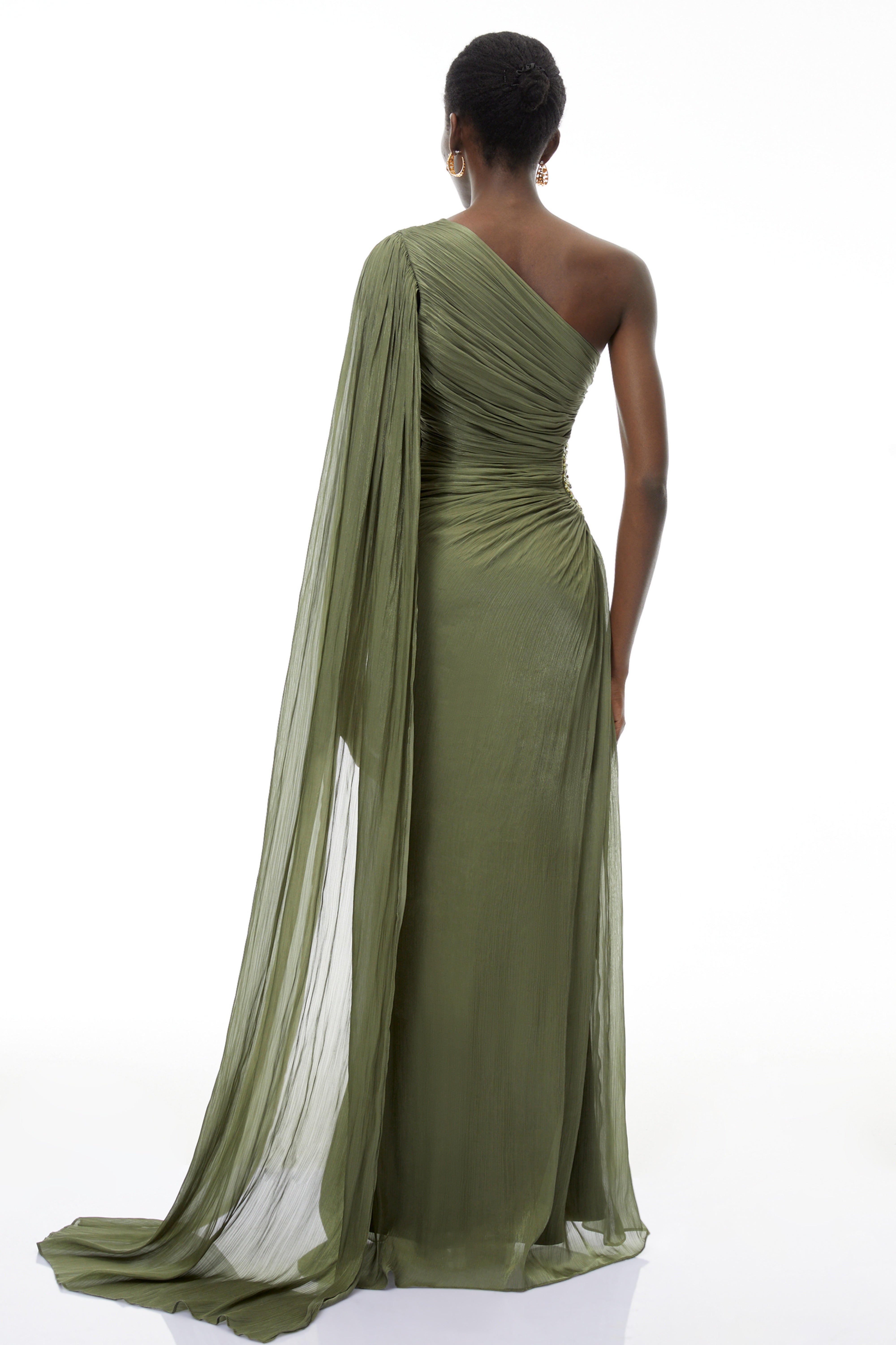 Olive green pleated one-shoulder gown with beaded embellishments and a long draped shoulder cape