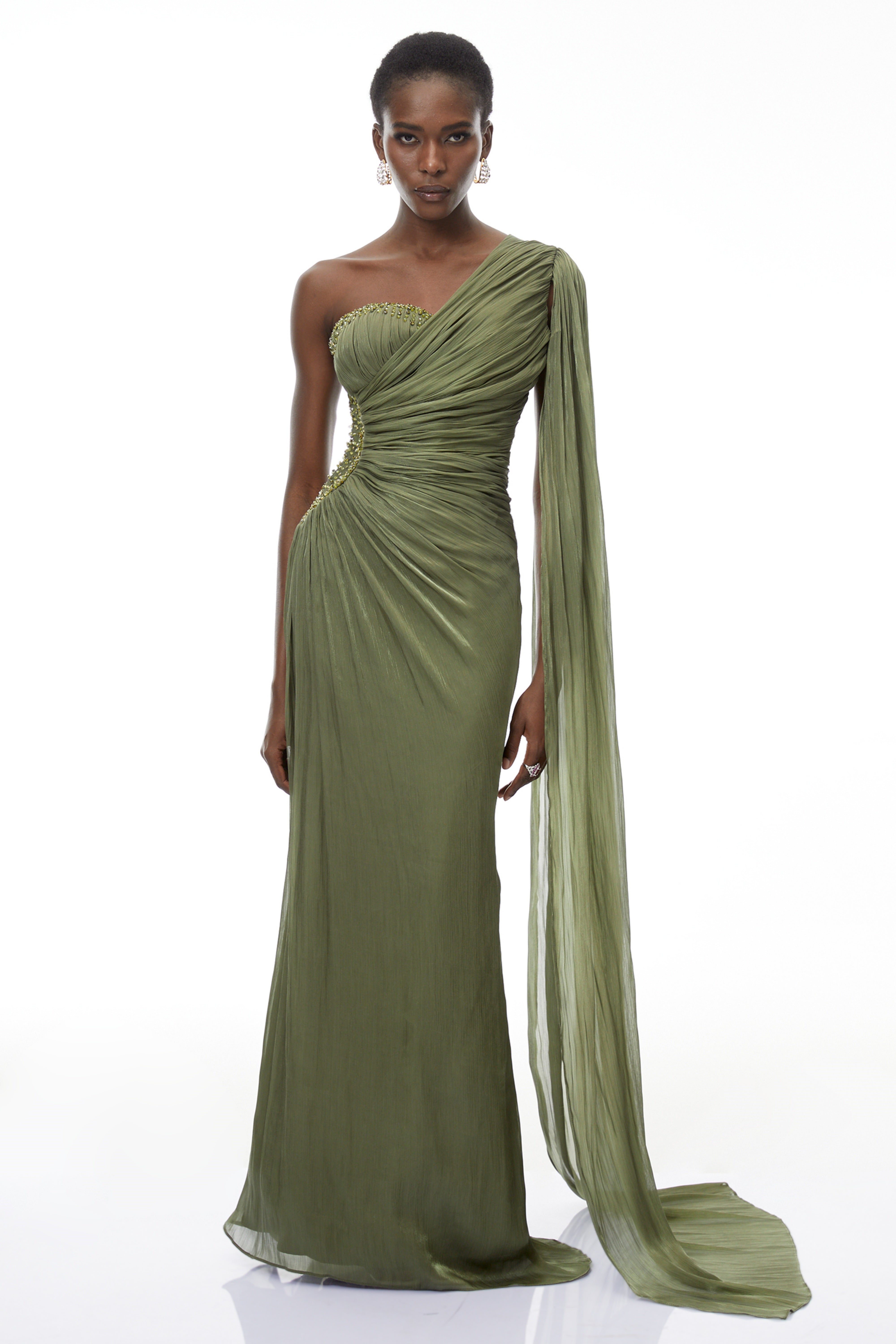 Olive green pleated one-shoulder gown with beaded embellishments and a long draped shoulder cape