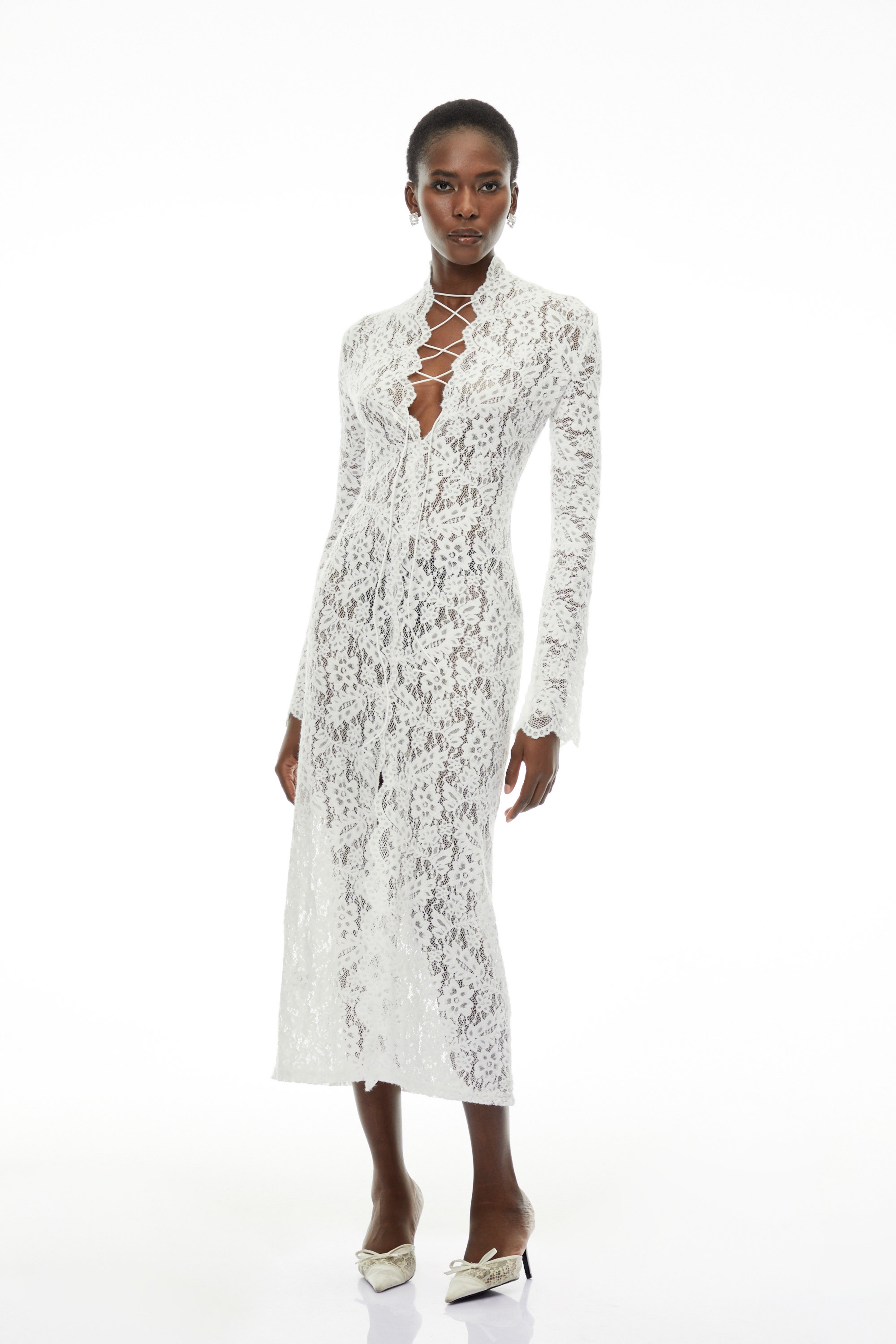 White lace maxi dress with a lace-up plunging neckline, long flared sleeves, and a high front slit