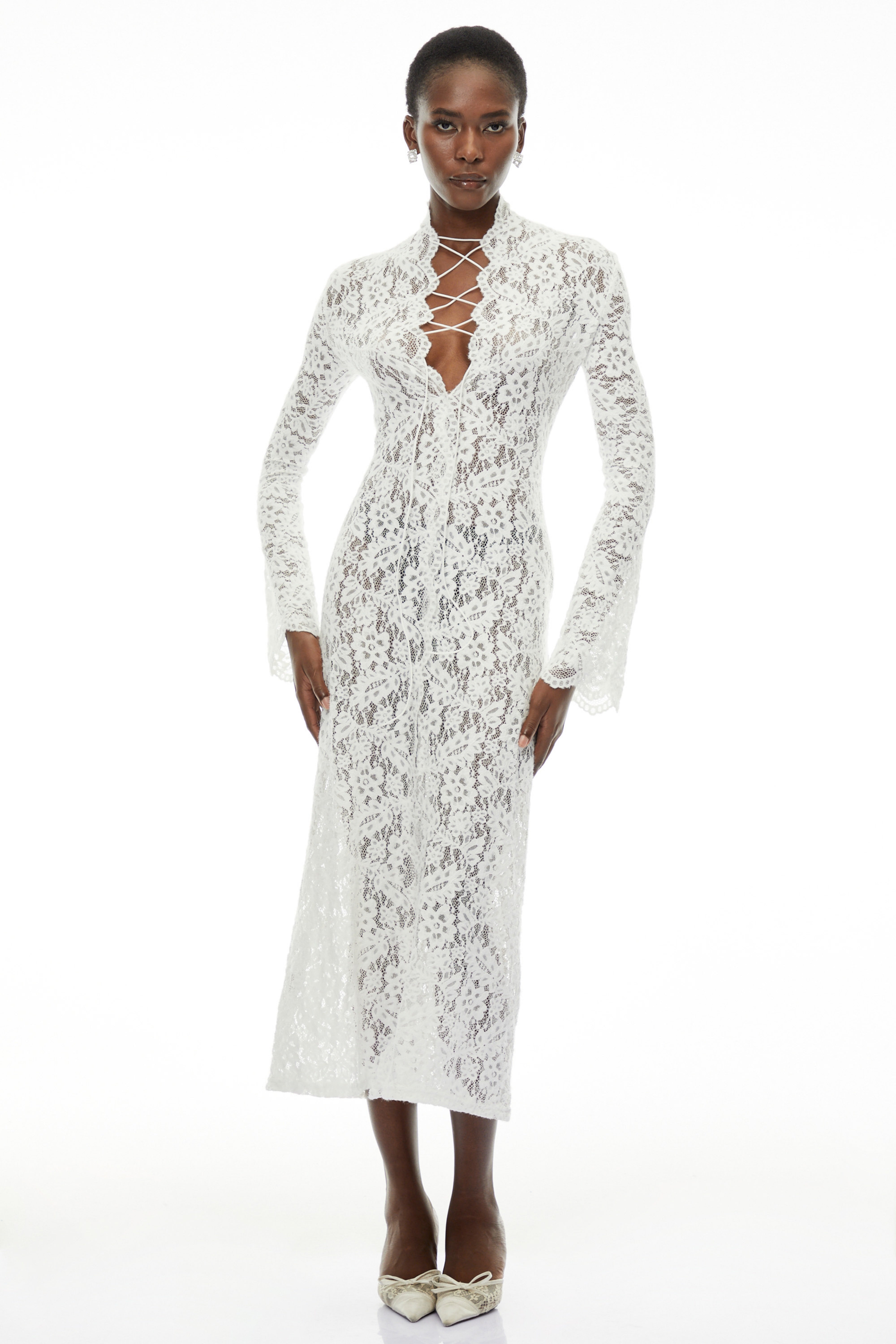 White lace maxi dress with a lace-up plunging neckline, long flared sleeves, and a high front slit