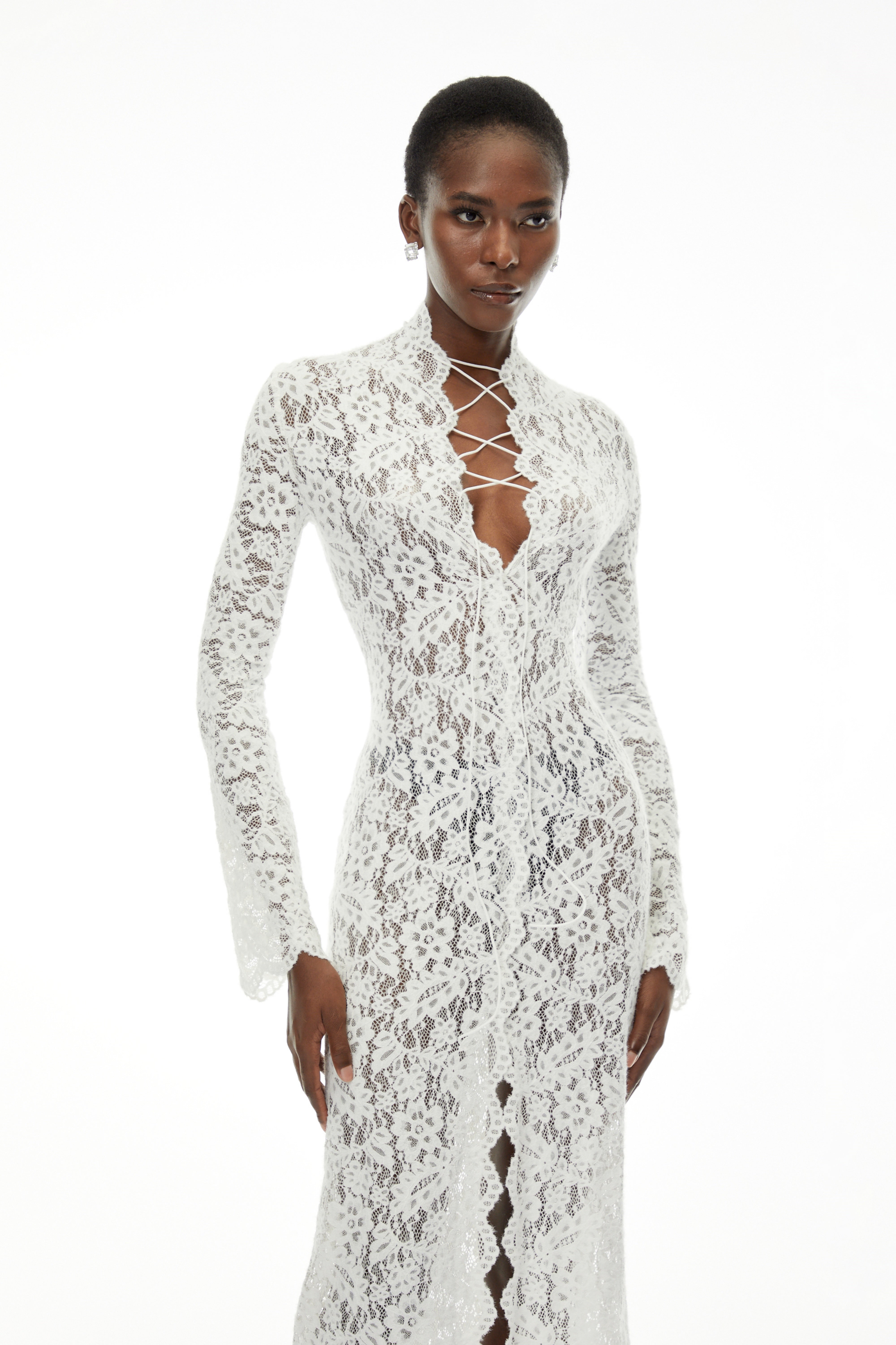 White lace maxi dress with a lace-up plunging neckline, long flared sleeves, and a high front slit