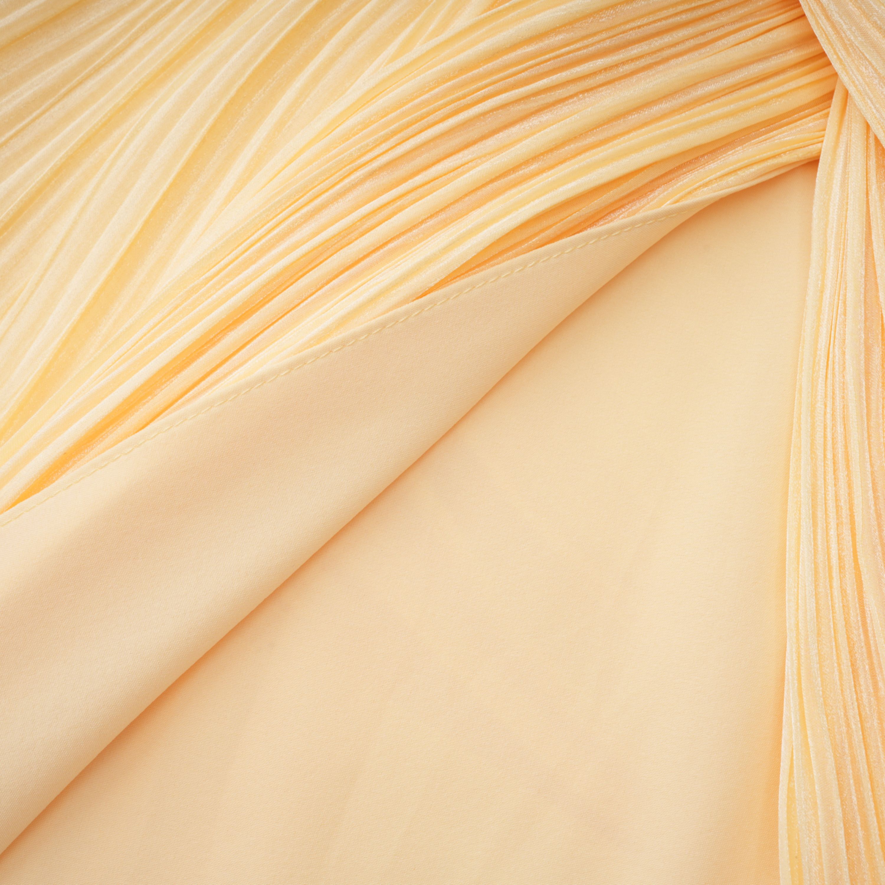 Pale yellow one-shoulder plissé maxi dress with a draped high slit and a trailing hem
