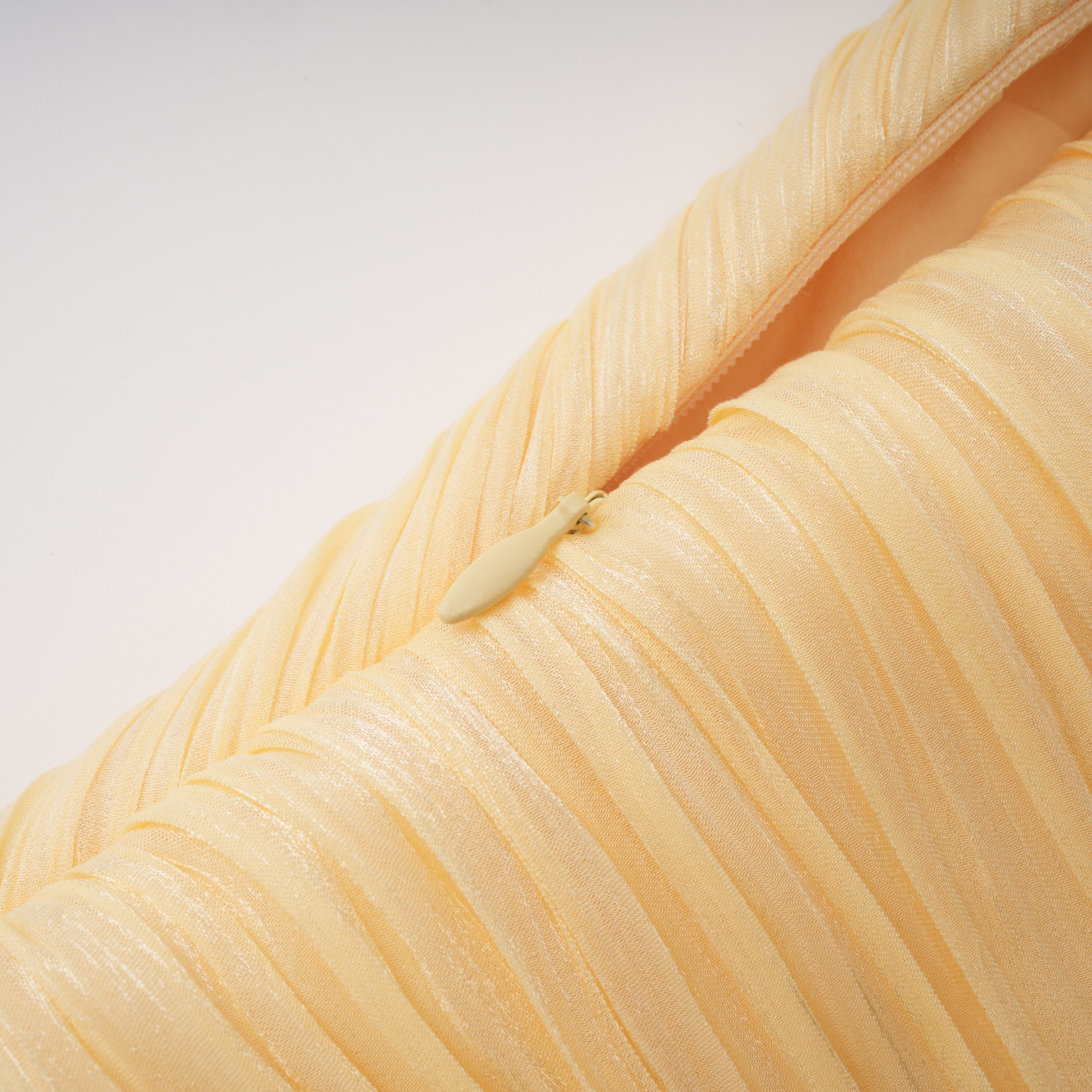 Pale yellow one-shoulder plissé maxi dress with a draped high slit and a trailing hem