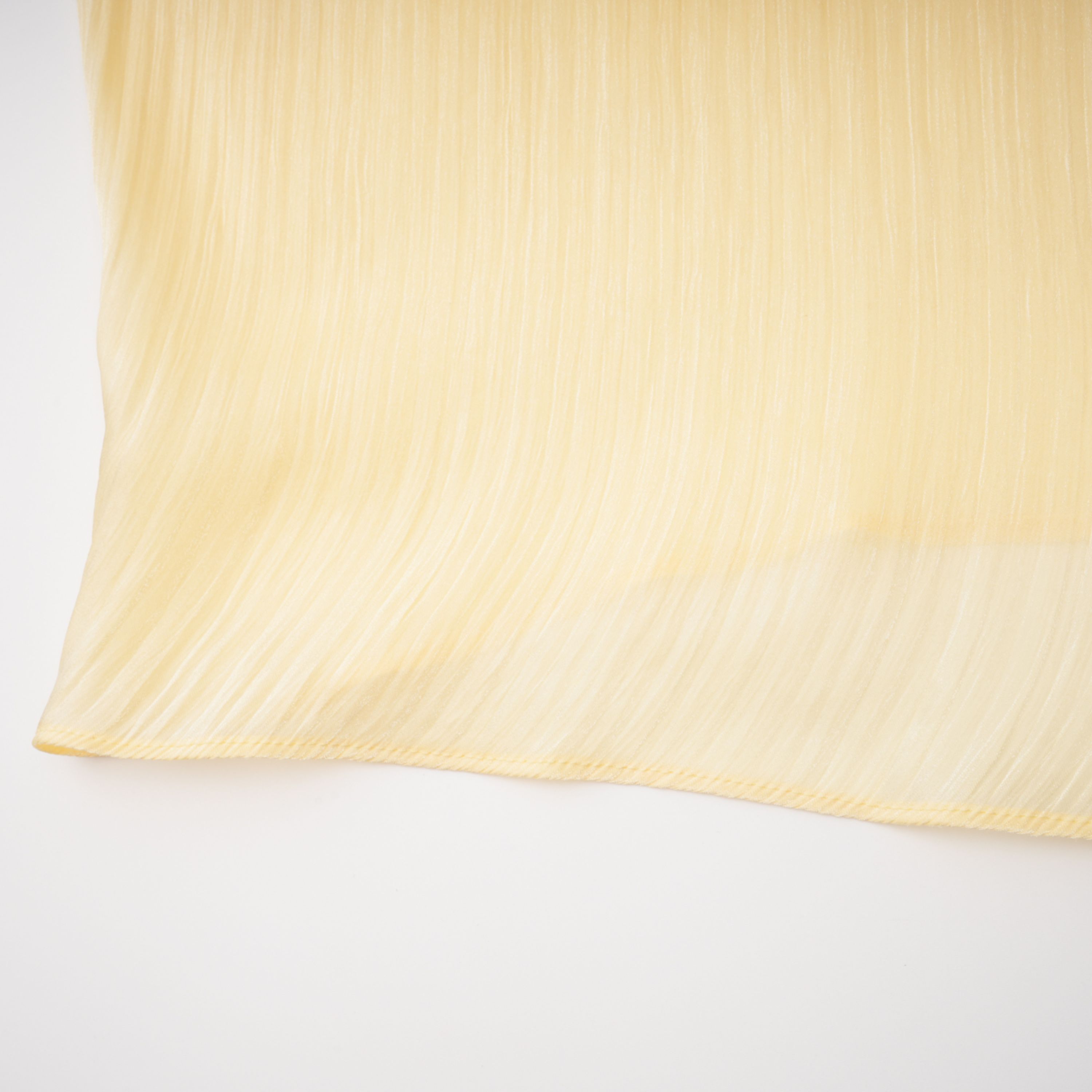 Pale yellow one-shoulder plissé maxi dress with a draped high slit and a trailing hem