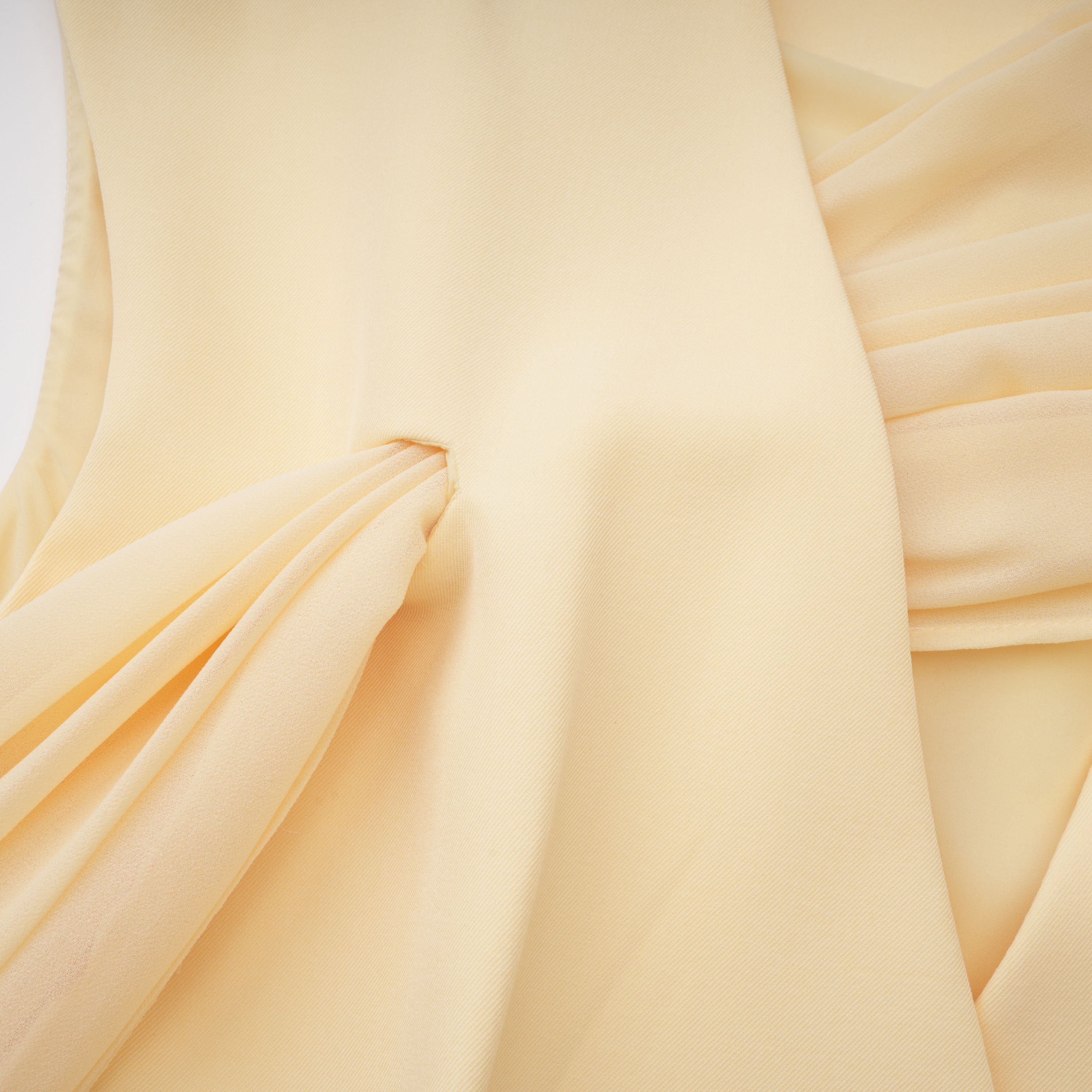 Pale yellow top and trousers set with an asymmetric blazer bodice, draped sheer neckline, and cape panels