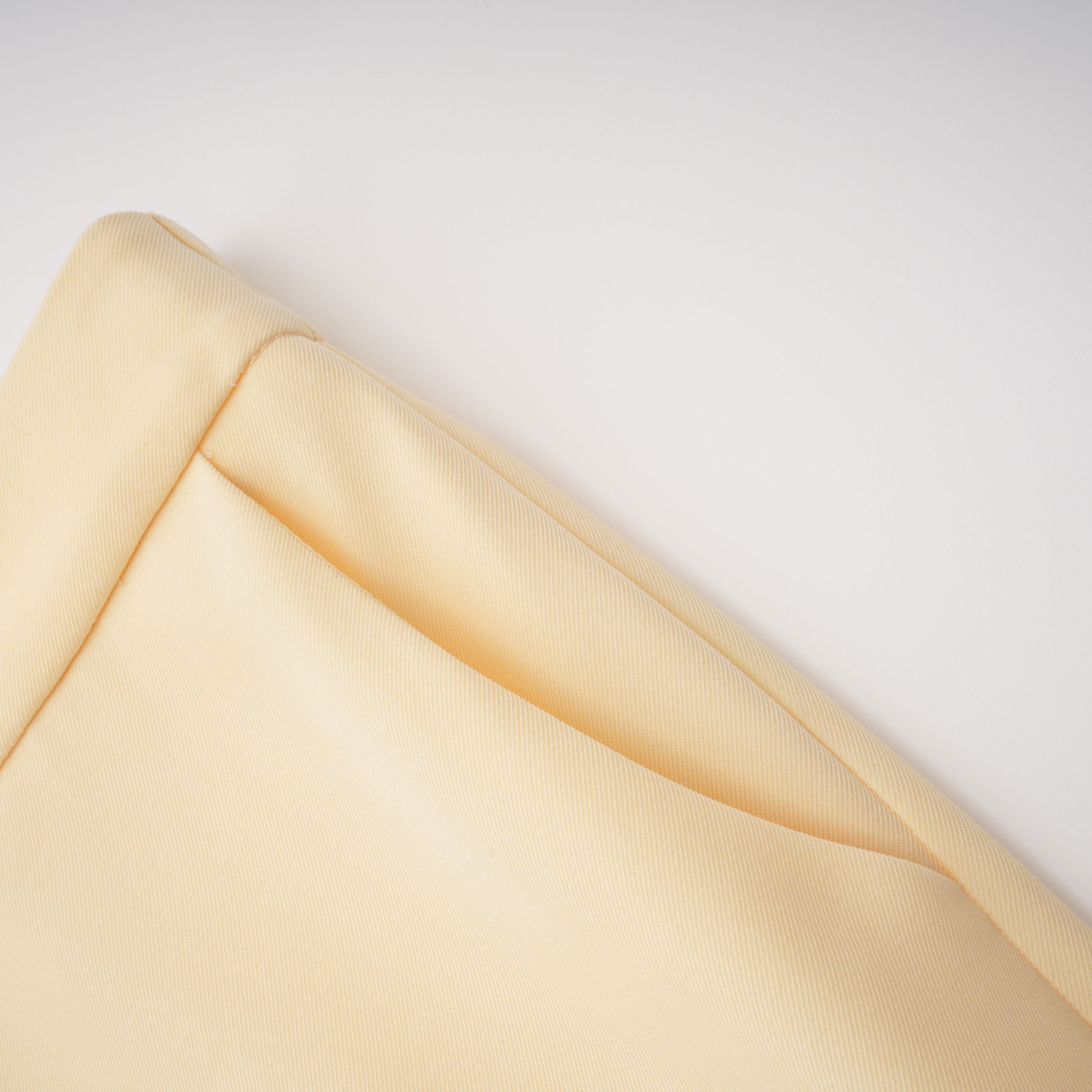 Pale yellow top and trousers set with an asymmetric blazer bodice, draped sheer neckline, and cape panels