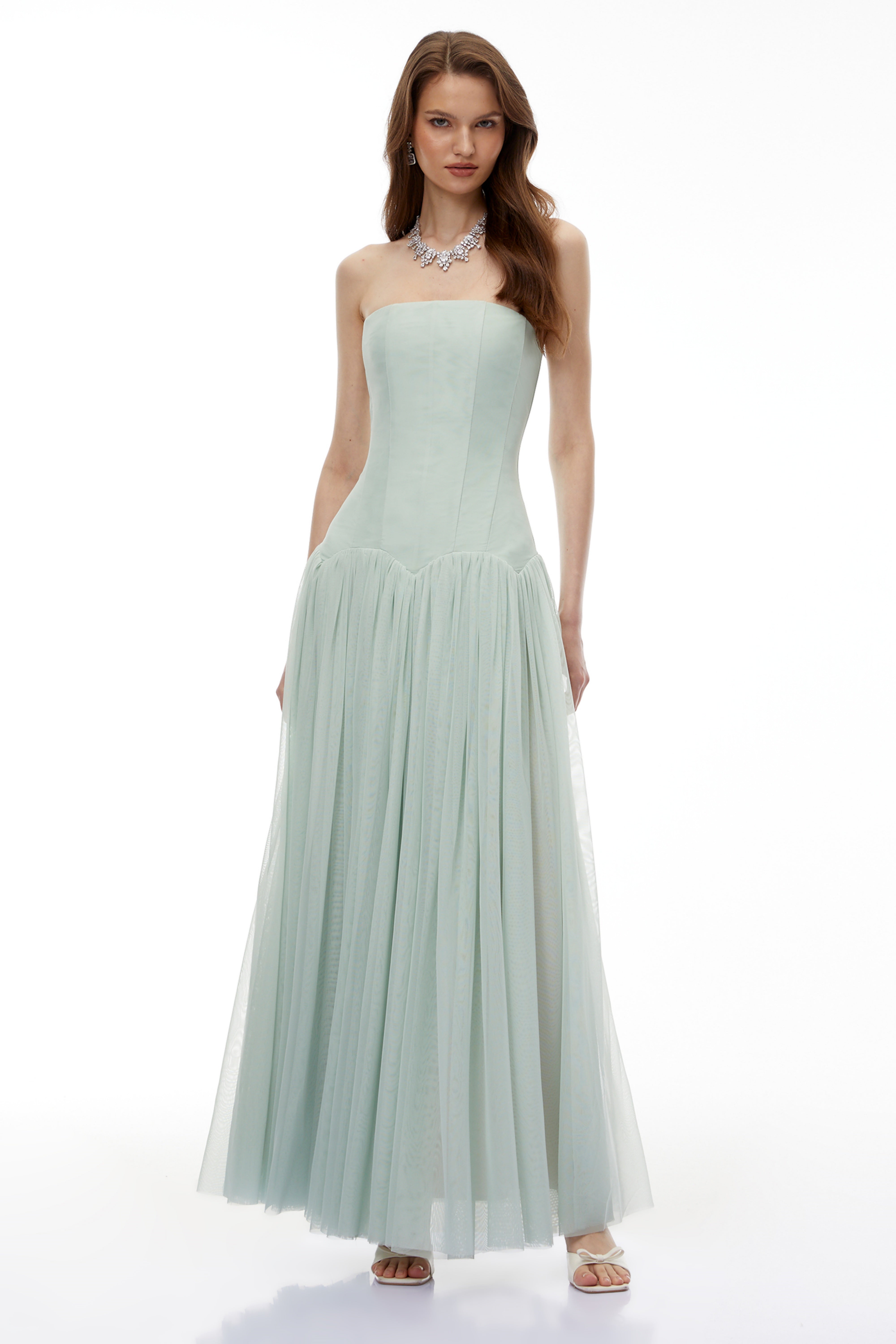 Sage green strapless gown with a corset-style bodice and flowing pleated skirt