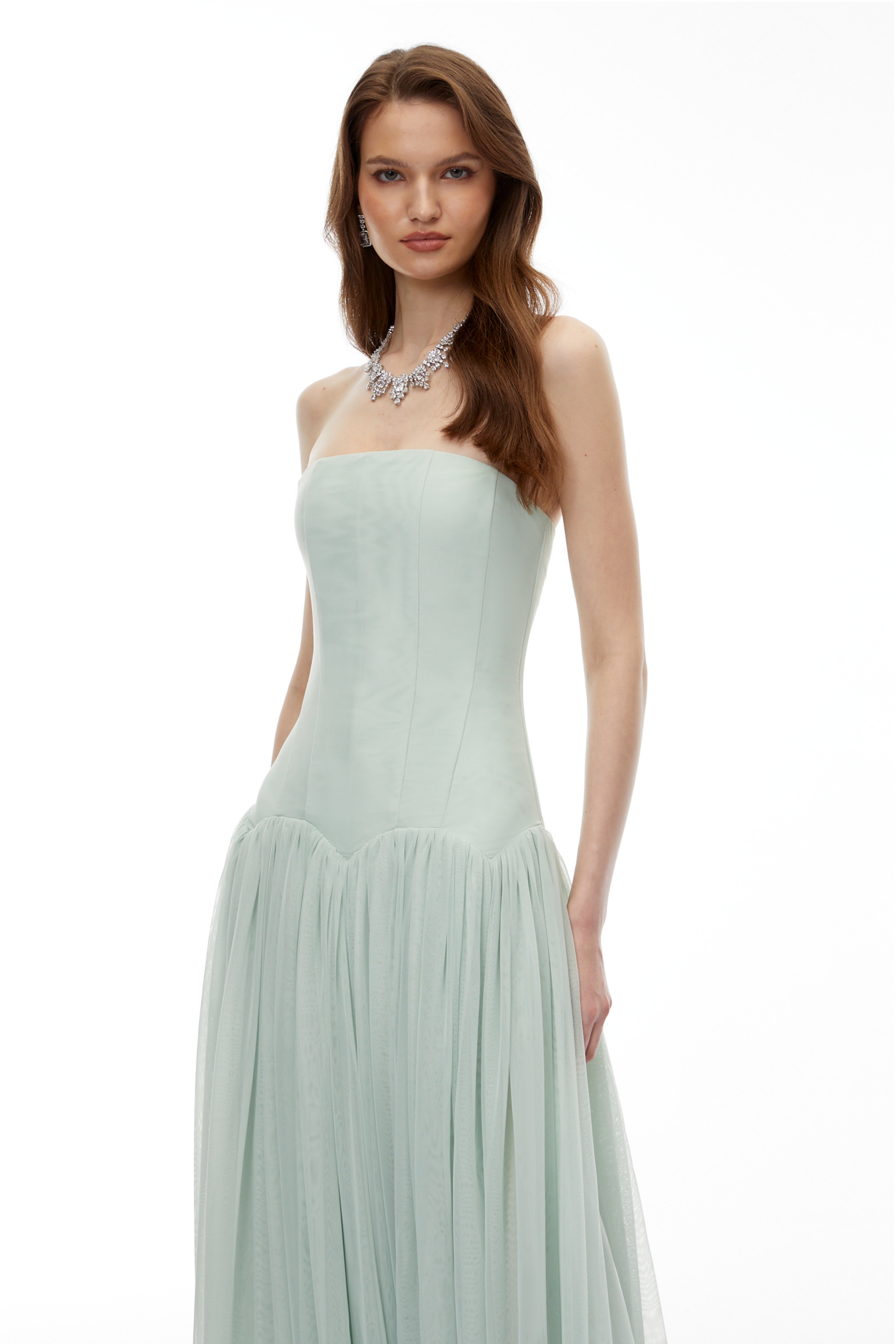 Sage green strapless gown with a corset-style bodice and flowing pleated skirt