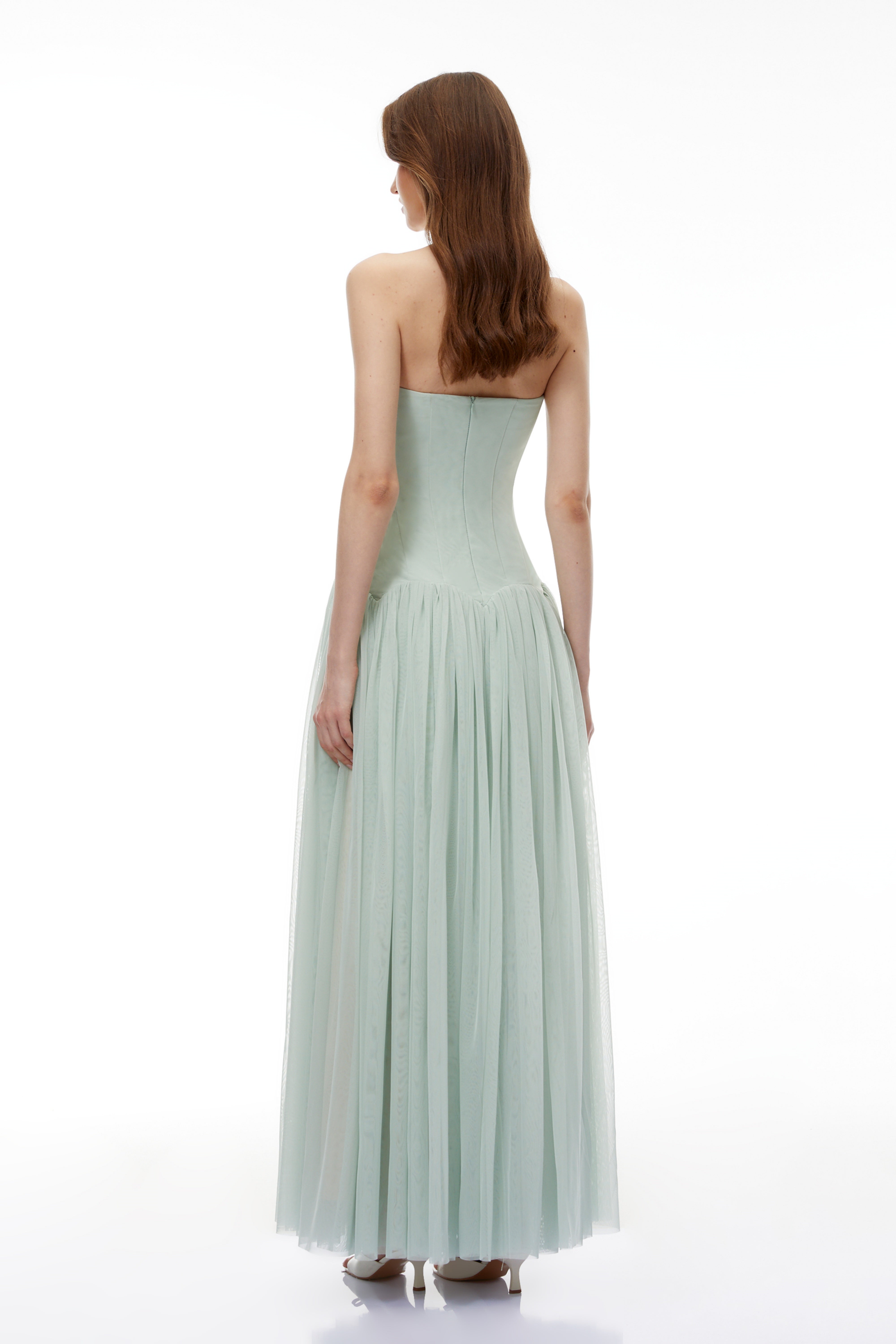 Sage green strapless gown with a corset-style bodice and flowing pleated skirt