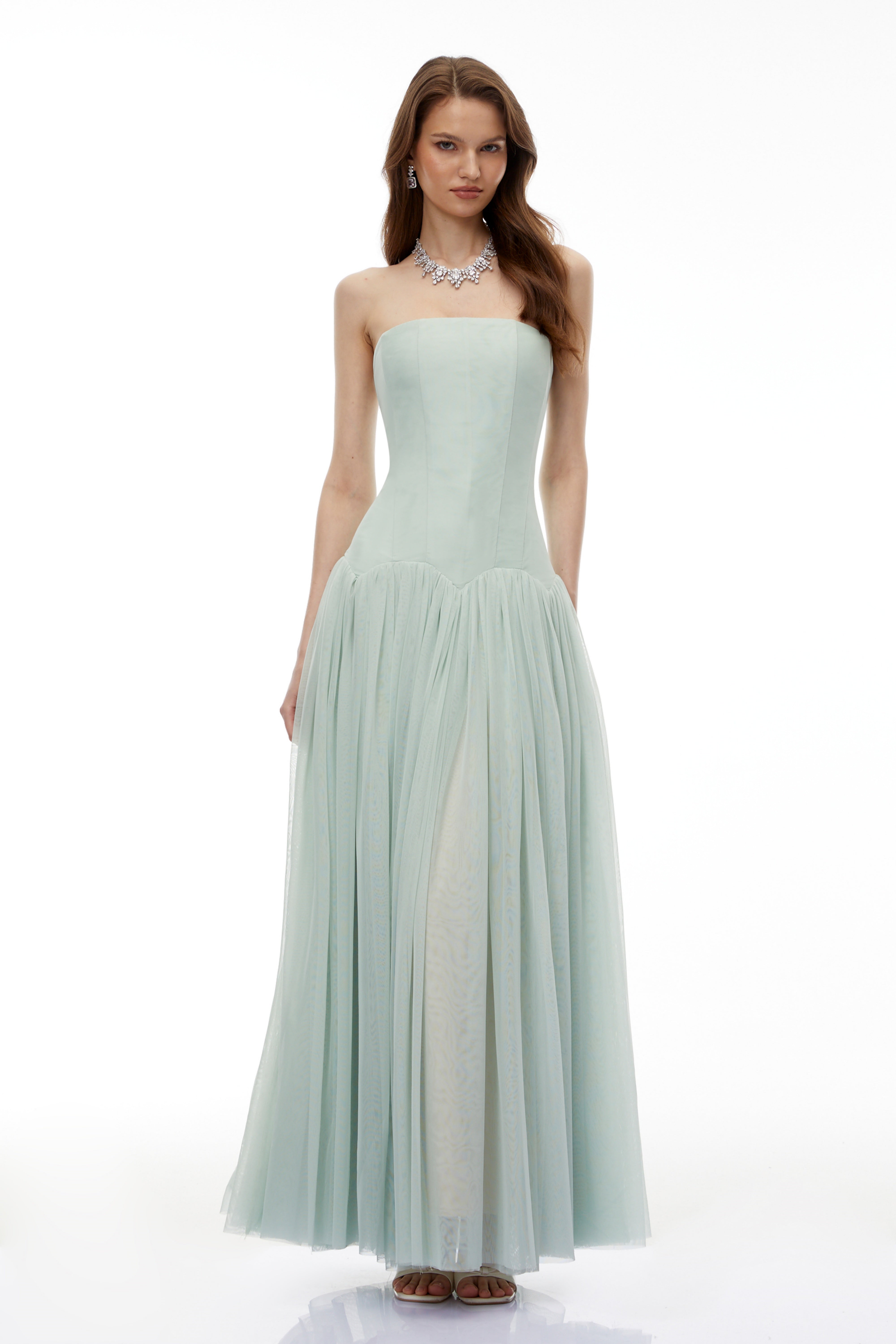 Sage green strapless gown with a corset-style bodice and flowing pleated skirt