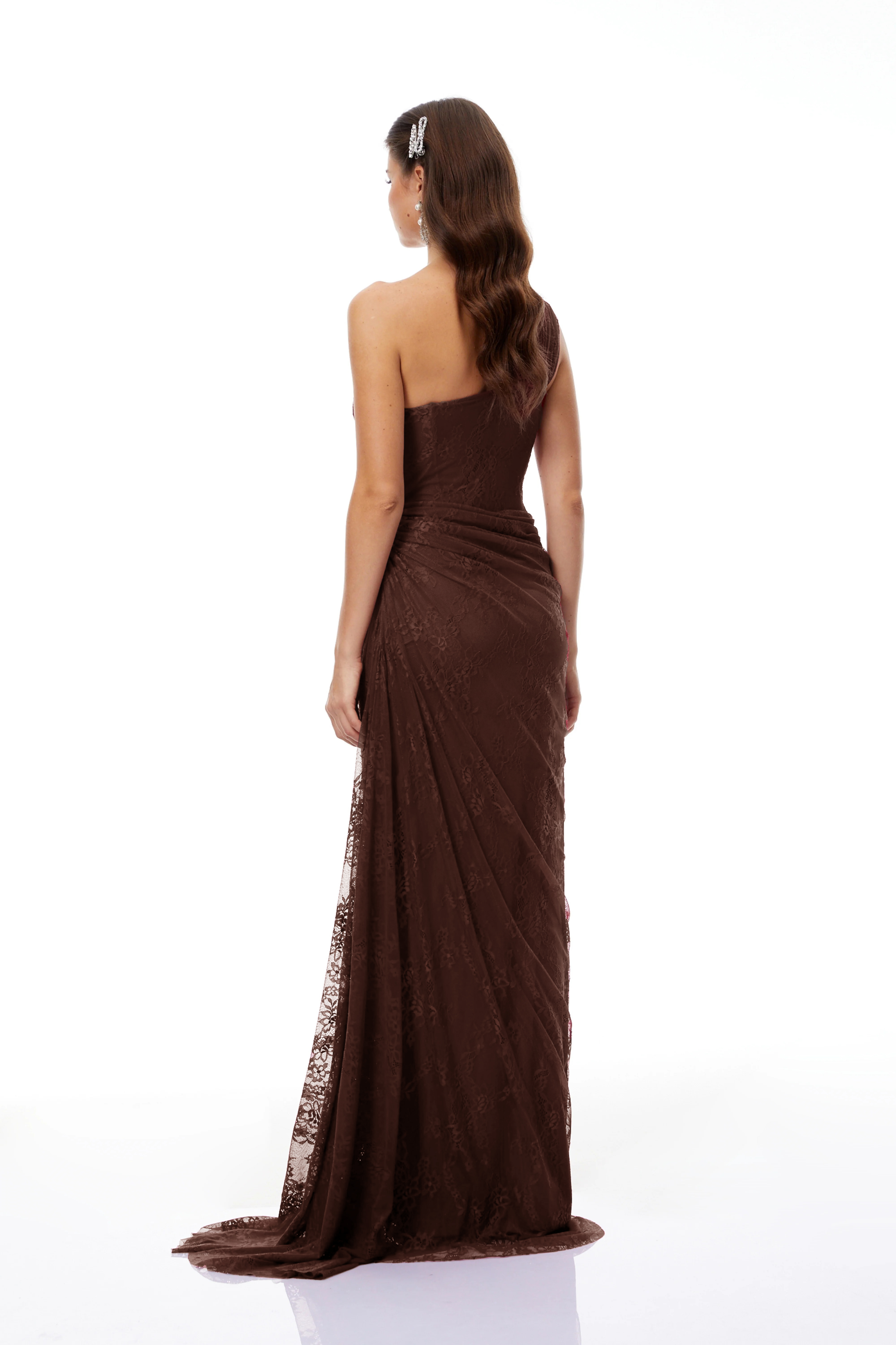 Brown lace maxi dress with a one-shoulder neckline, structured corset bodice, and draped asymmetric skirt