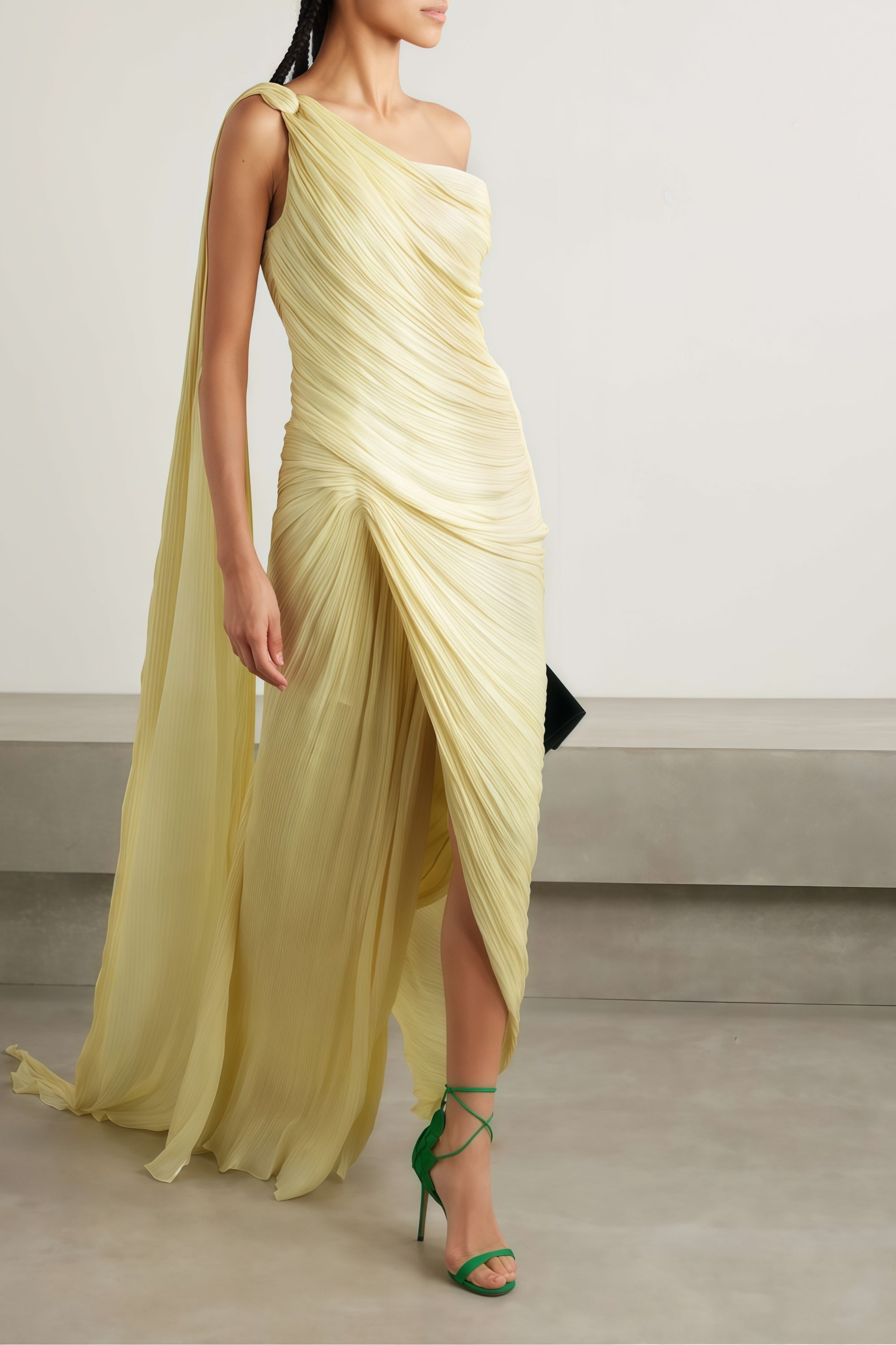 Pale yellow one-shoulder plissé maxi dress with a draped high slit and a trailing hem