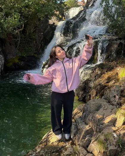 Model wearing the pink reactive jacket by a waterfall