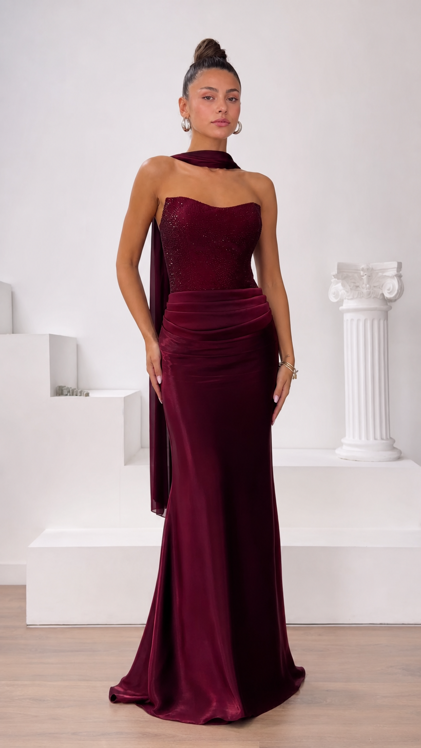 Front view of model wearing strapless burgundy embellished corset maxi gown with neck scarf