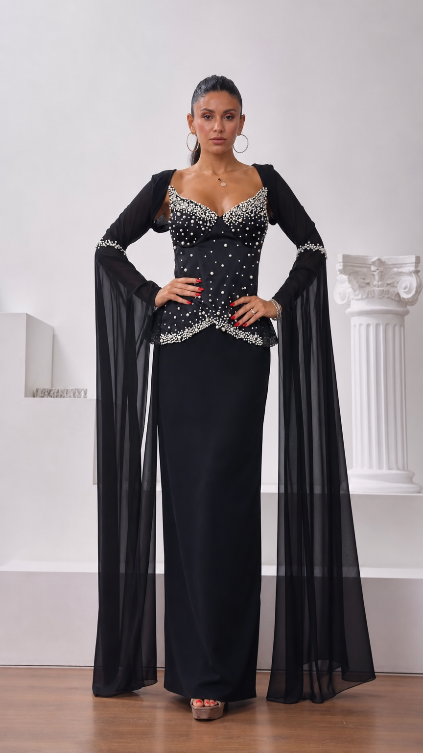 Front view of model wearing black pearl-embellished corset maxi dress with long chiffon cape sleeves