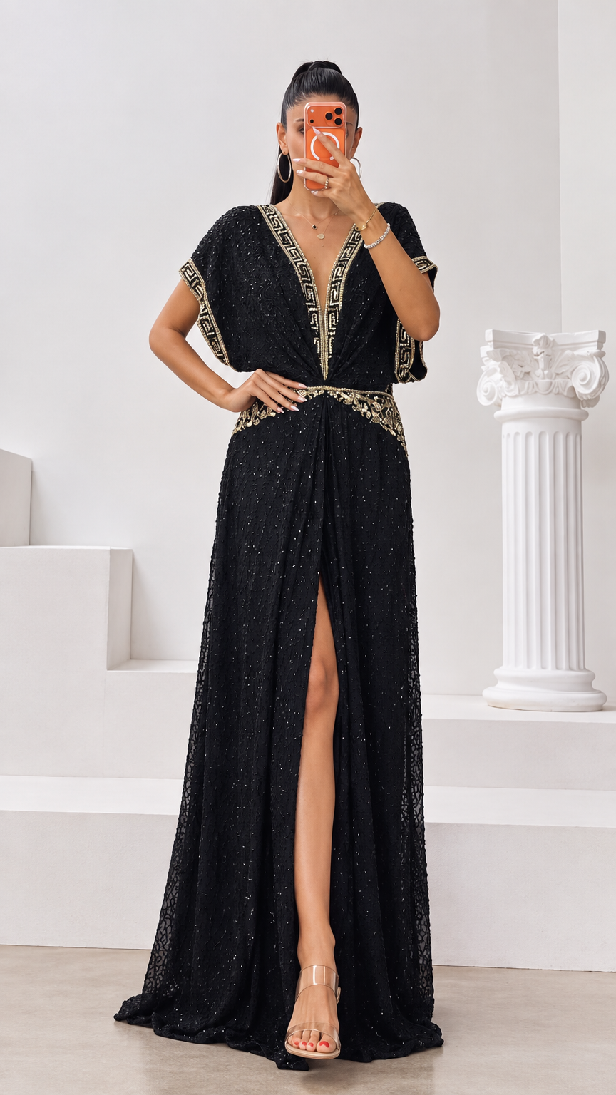 Front full-length view of woman wearing black shimmer maxi dress with gold embroidered trim and front slit