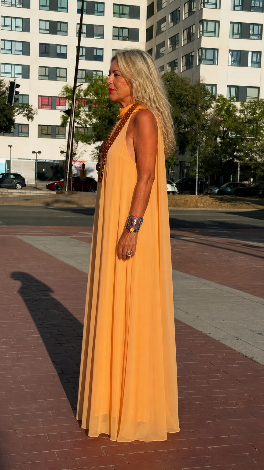 Side profile view of woman modeling orange flowy chiffon maxi dress