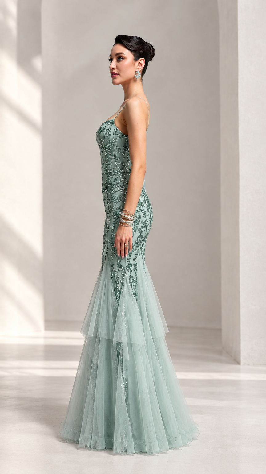 Side profile of model in sage green sequin tulle evening gown showing fitted silhouette and flared tiered hem