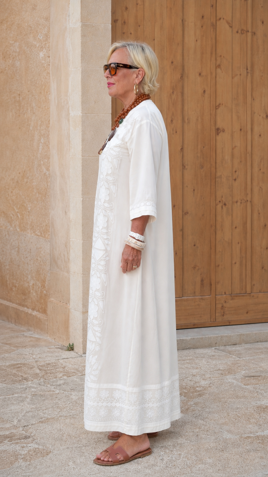 Side view of woman in white embroidered kaftan maxi dress