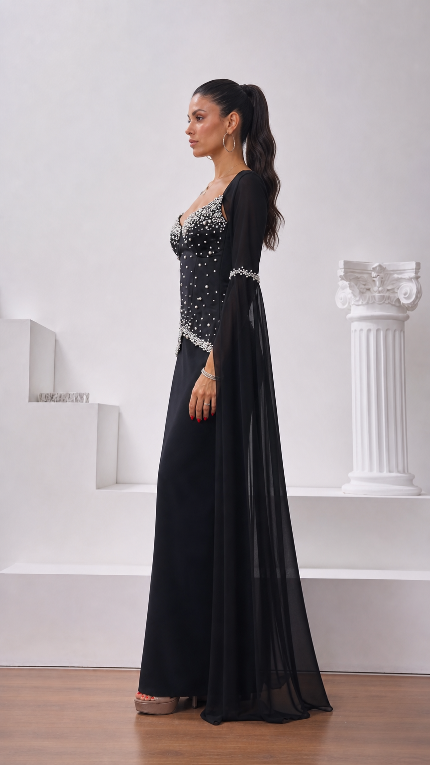 Side profile view of black evening gown showing corset structure and flowing cape sleeve detail