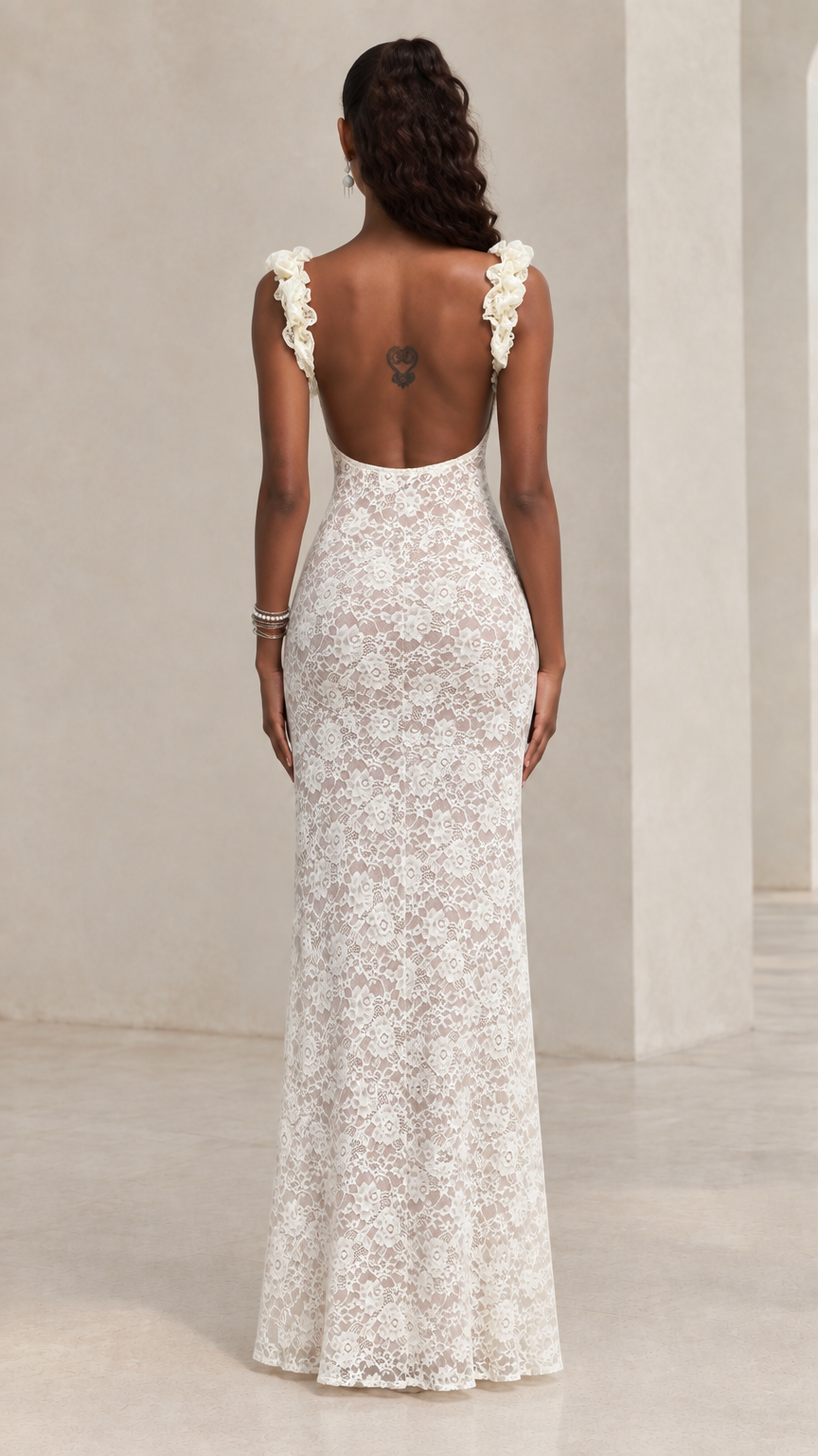 Back view of white lace maxi dress featuring deep scoop open back and ruffled straps