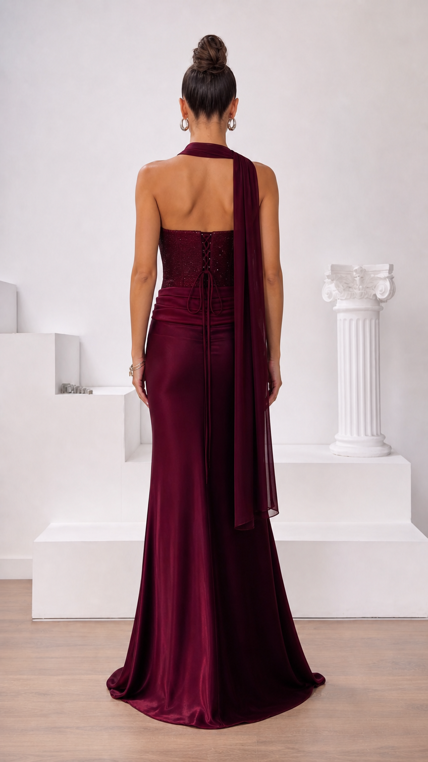 Back view of burgundy corset evening dress highlighting lace-up closure and trailing scarf