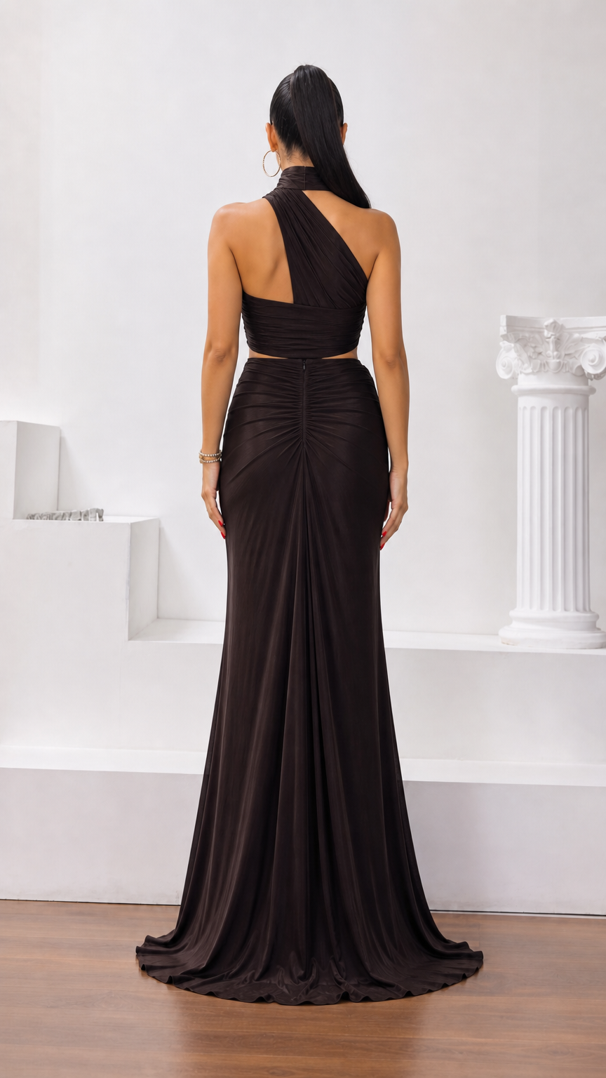 Back view of dark brown halter maxi gown showing asymmetrical back strap and flowing skirt