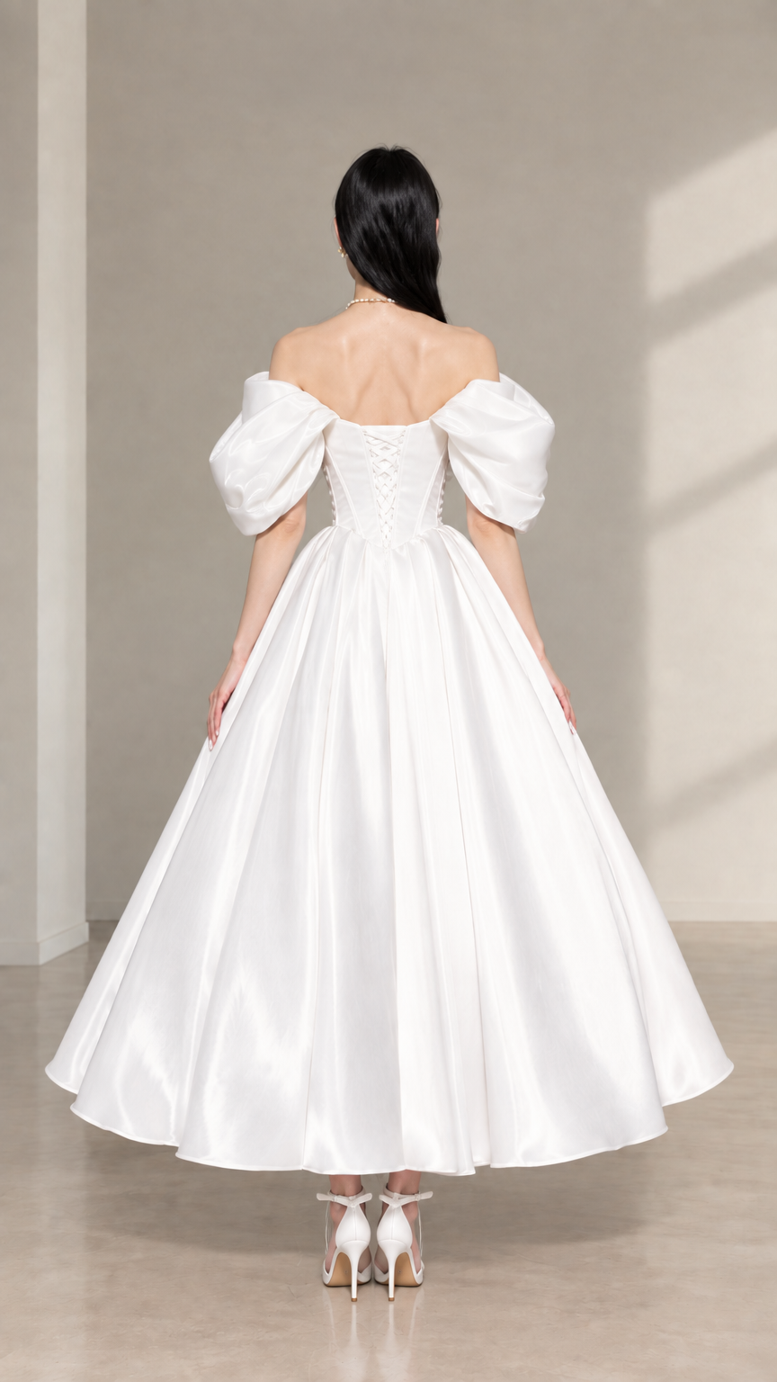 Back view of white satin corset midi dress featuring lace-up back detailing