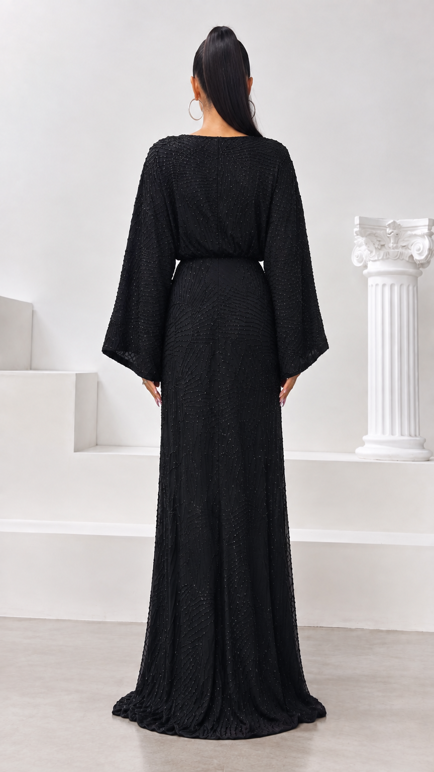 Back view of black beaded evening dress with fitted waist and flowing hem