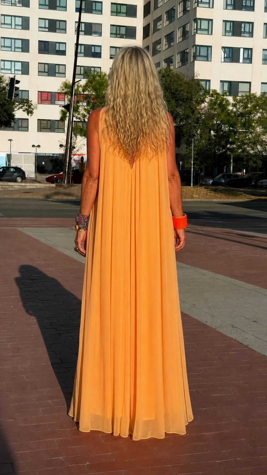 Back view of woman wearing orange high neck sleeveless trapeze maxi dress