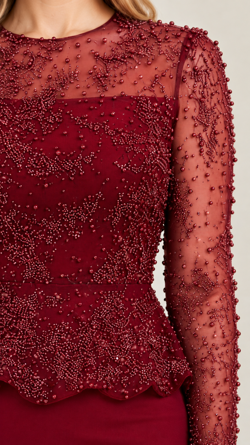 Close-up detail of sheer illusion neckline and intricate burgundy beading on peplum bodice
