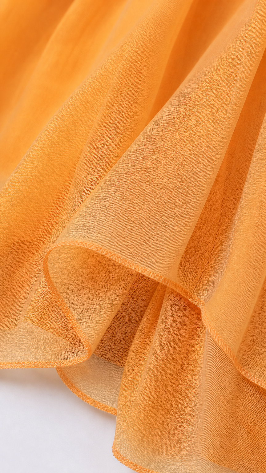 Close-up detail of lightweight sheer orange chiffon fabric and hem finish