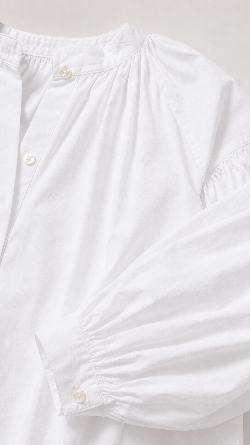 Close-up detail of white button placket and gathered neckline with cuff