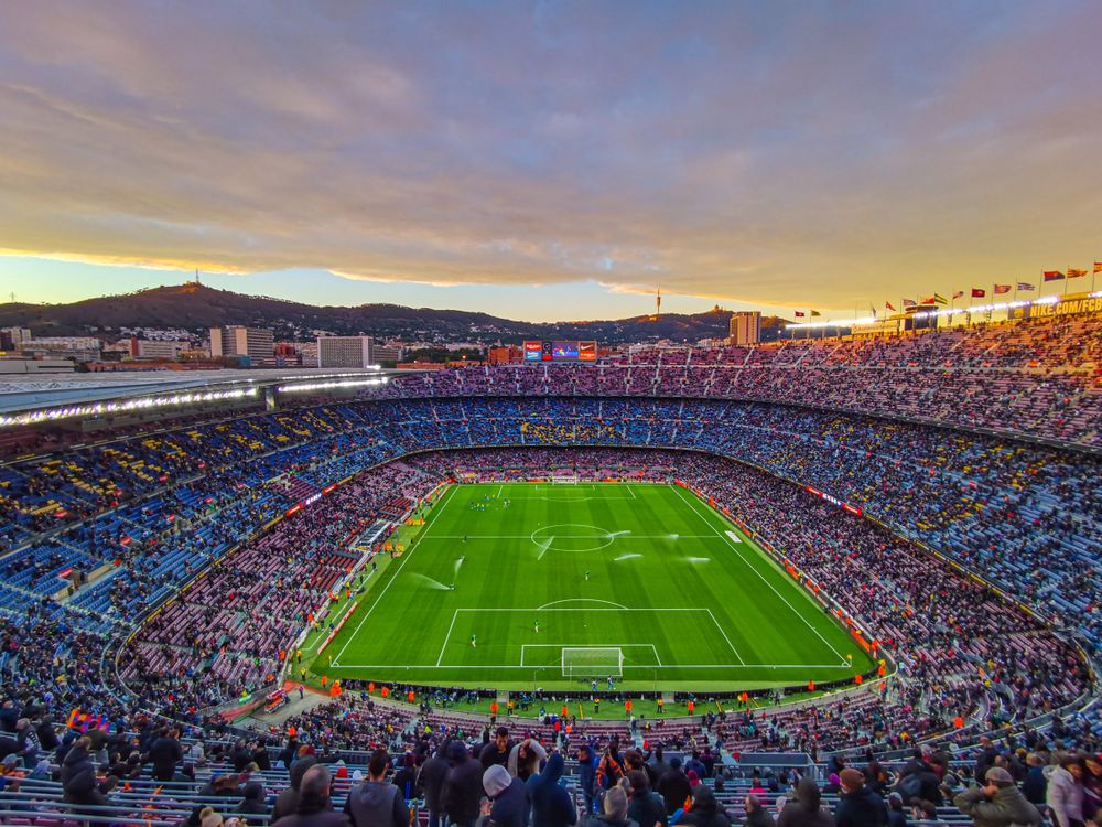 Archieffoto van Camp Nou bij zonsondergang, met supporters op de tribunes en het voetbalveld in beeld
