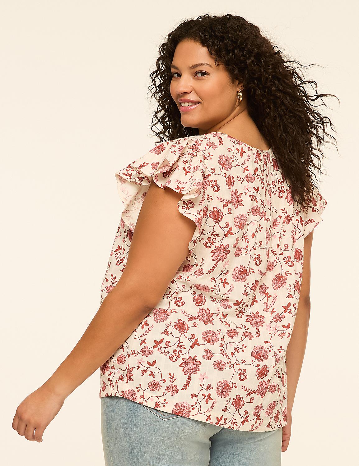 A woman with curly dark hair smiles over her shoulder, wearing a floral print blouse and light blue jeans against a plain cream background. Product Image 2