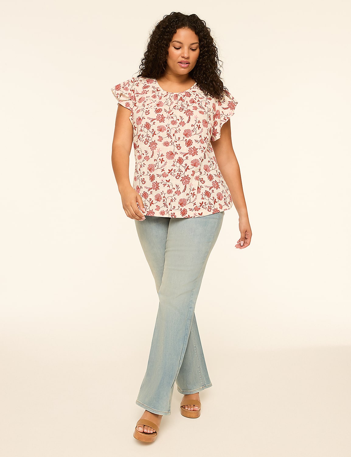 A woman in a floral top and light wash jeans stands against a plain, light-colored background. Product Image 3