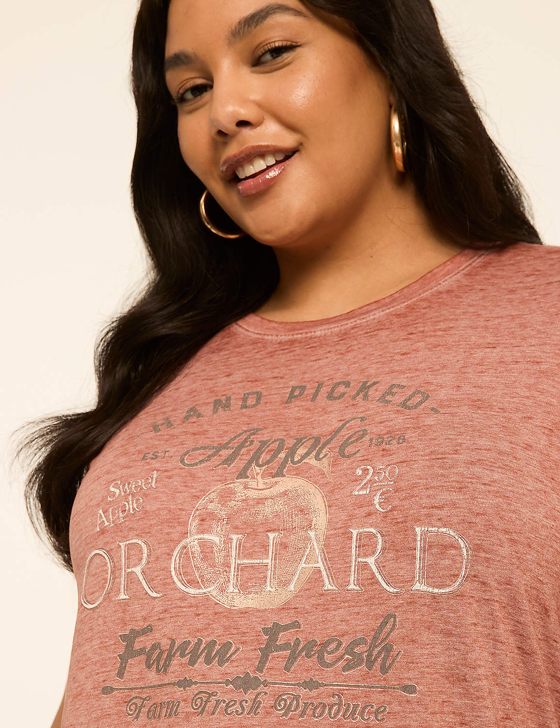 A close-up of a woman wearing a distressed pink t-shirt with "Apple Orchard Farm Fresh" printed on it, against a plain background. Product Image 4