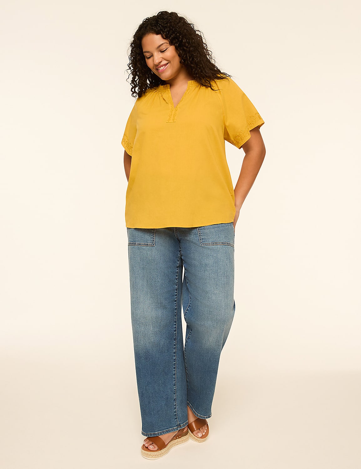 A smiling woman in a yellow top and blue jeans stands against a plain, light-colored background. Product Image 3