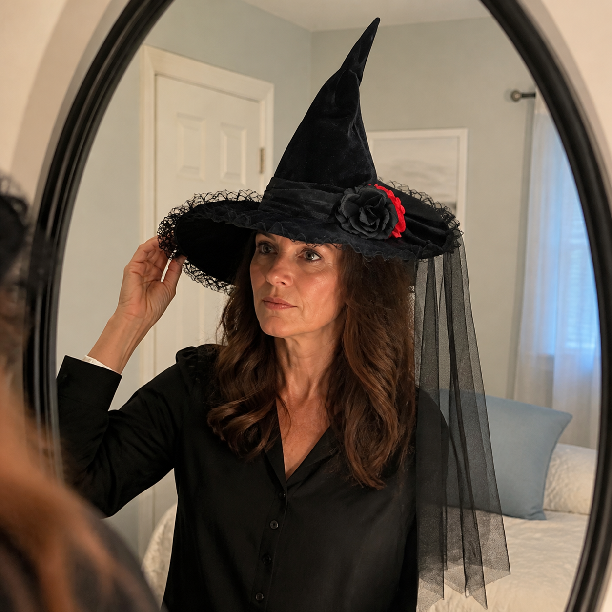 Woman adjusting the Baroque veil witch hat in a bedroom mirror