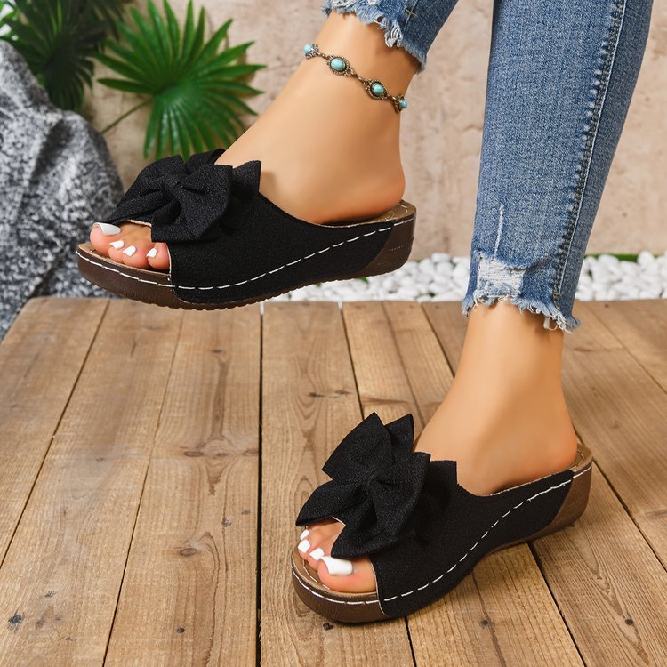 Bow-detail open-toe wedge slide sandals shown on feet