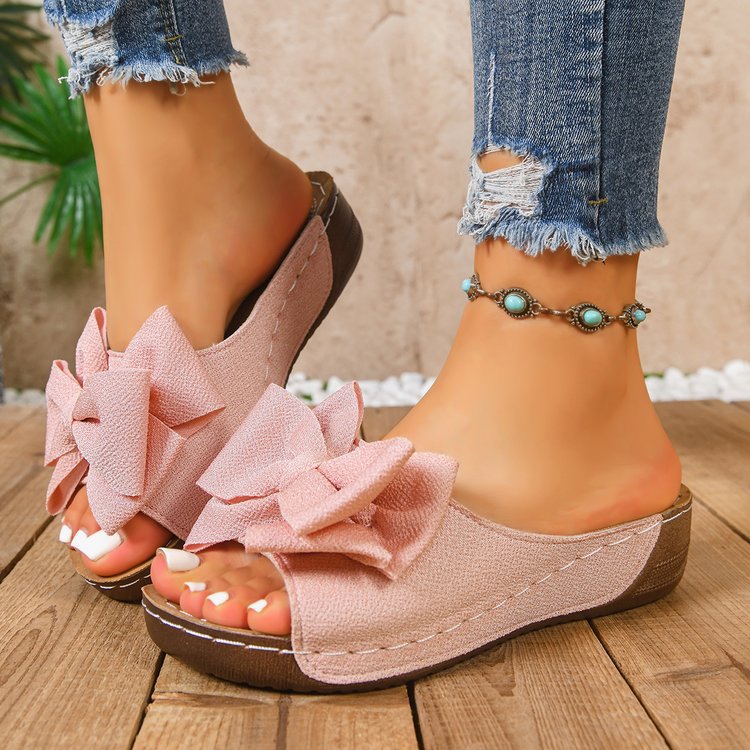 Bow-detail open-toe wedge slide sandals shown on feet