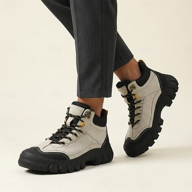 Man wearing gray and black chunky high-top lace-up boots with dark trousers