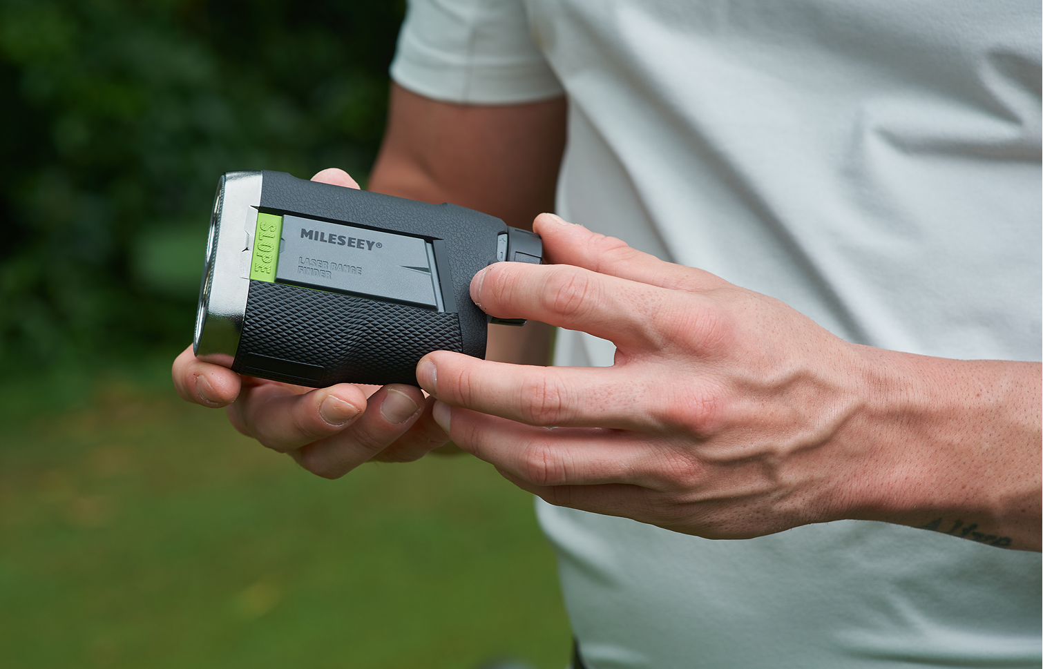 The golfer holding and adjusting the MILESEEY PF260 Tour golf rangefinder with slope switch