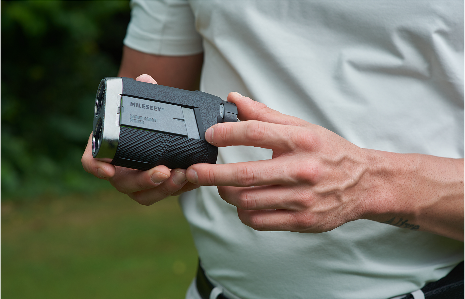 The golfer gripping and operating the MILESEEY PF260 Tour rangefinder golf device on golf course