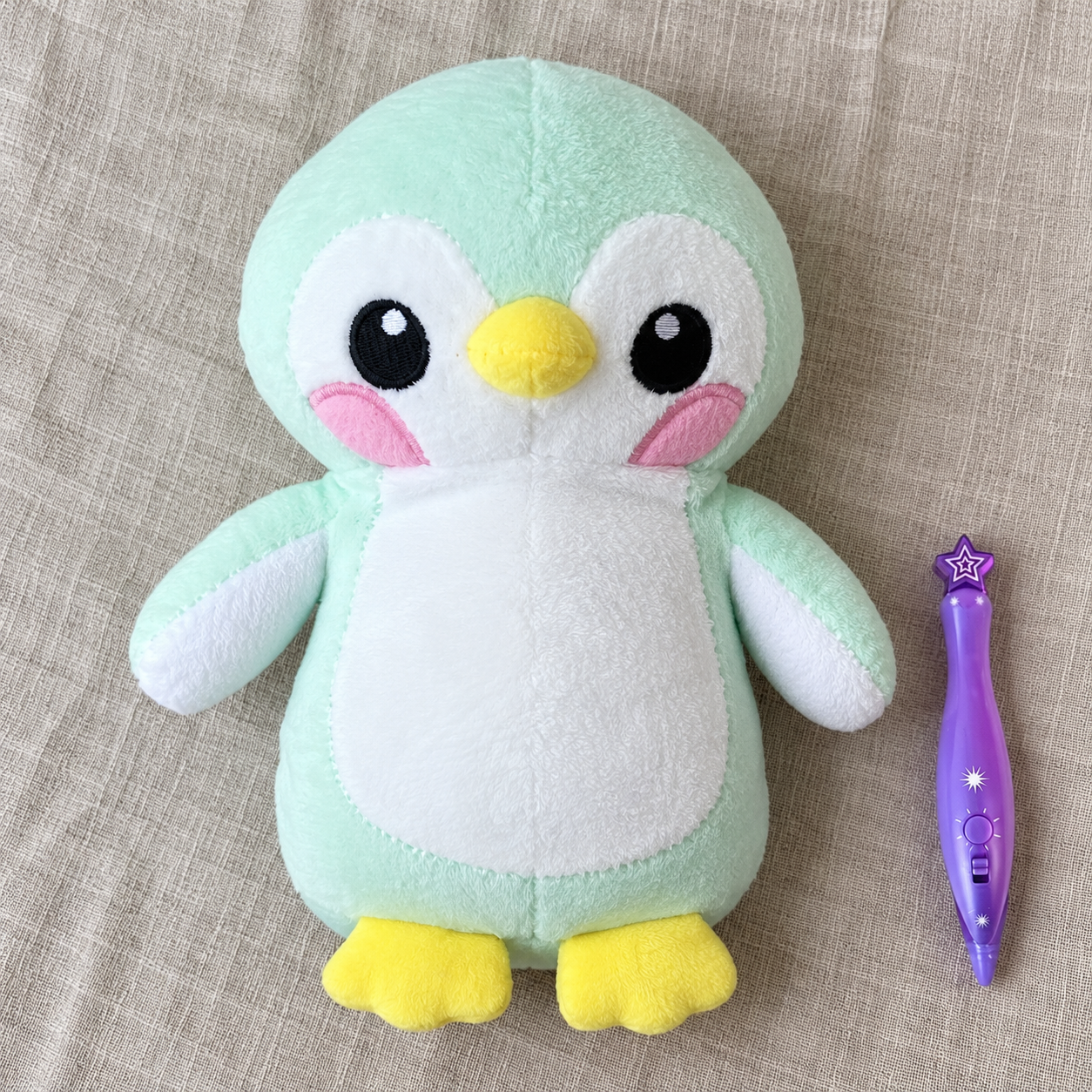 Ein einzelner hellgrüner Pinguin und ein violetter Stift auf einem Tisch