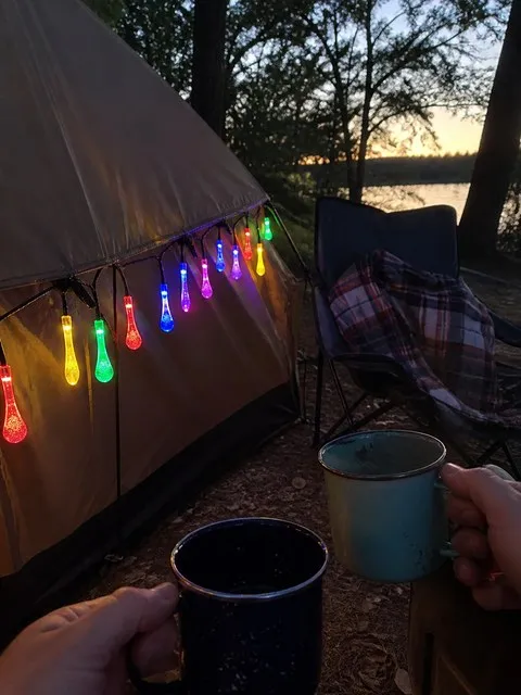 Multicolor teardrop lights hanging from a camping tent at dusk