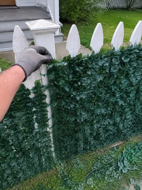 Artificial ivy privacy screen fitted around a white picket fence post