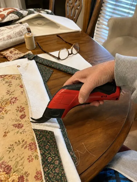 Red electric scissors beside a quilt project