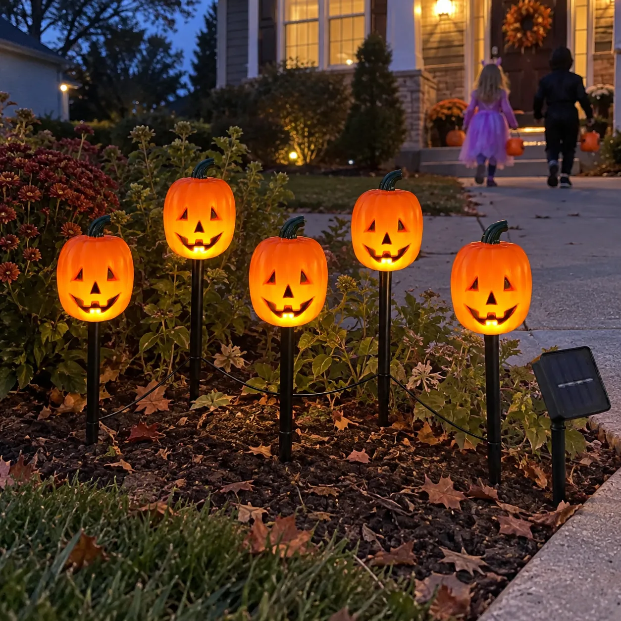 Pumpkin pathway lights guiding costumed children toward a porch
