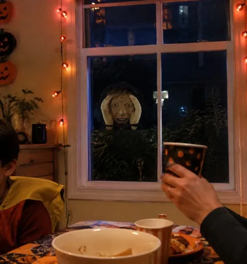Creepy peeper prop surprising guests during a Halloween dinner